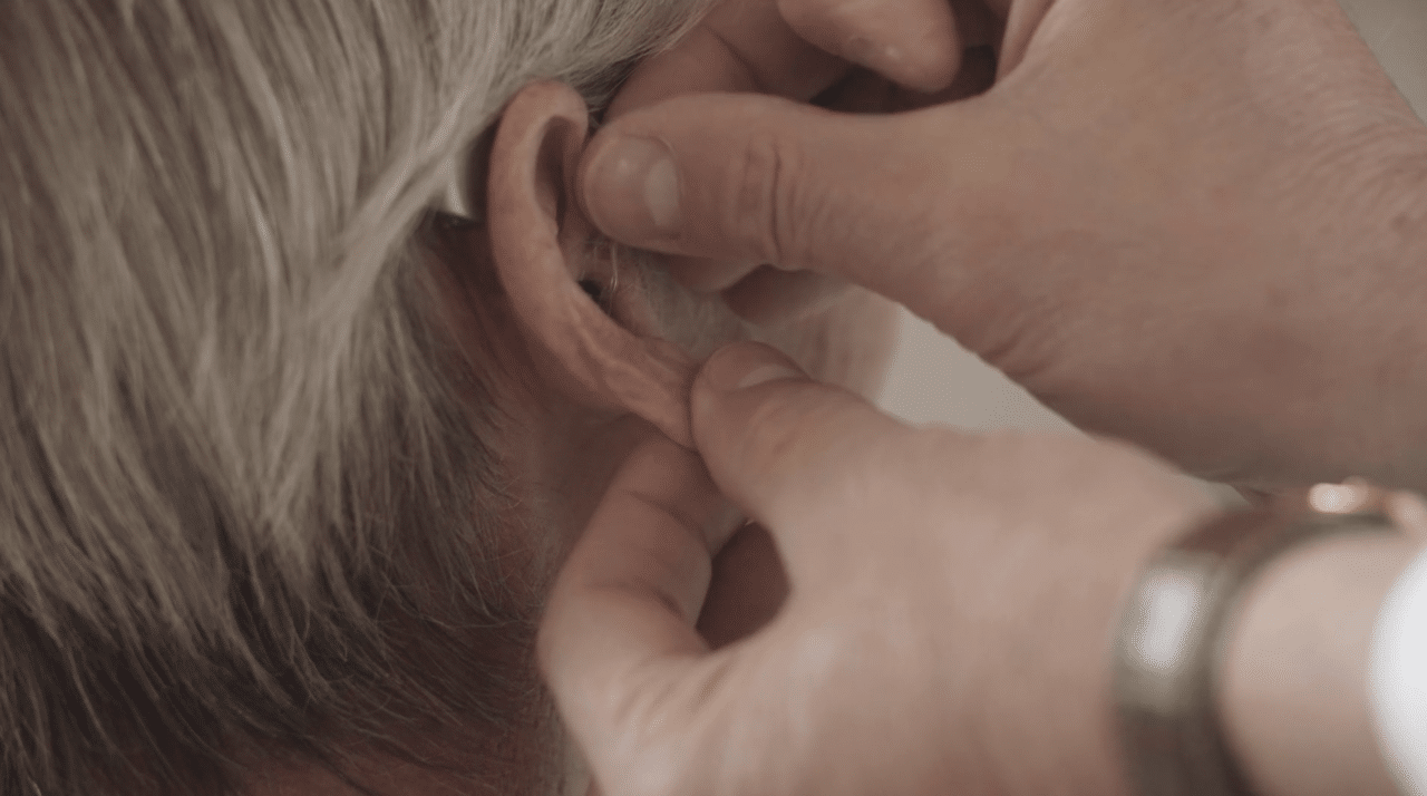A hearing aid being placed in a patient's ear