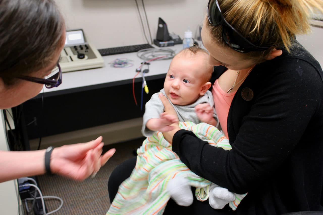 A baby held by an adult in an audiology office