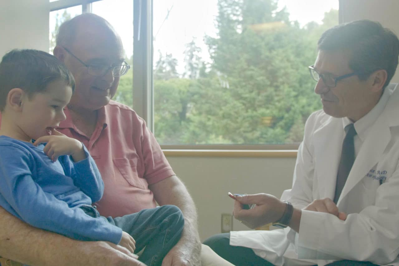 An audiologist showing a child and caretaker a hearing aid