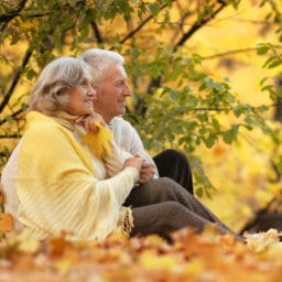 older couple sitting in the park in fall