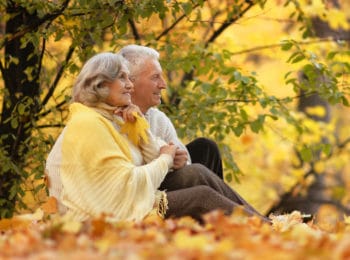 older couple sitting in the park in fall