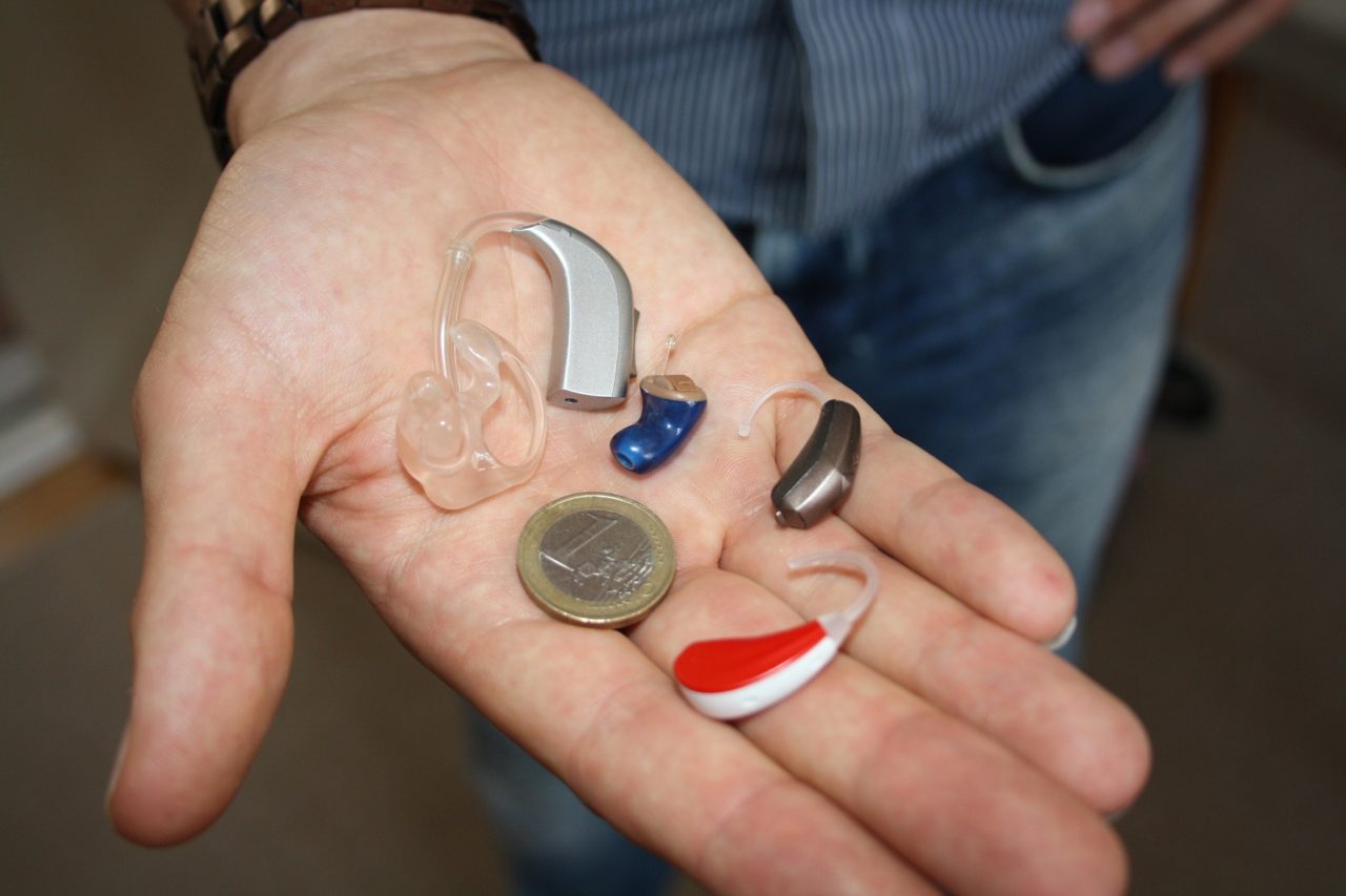 three different hearing aids and a coin