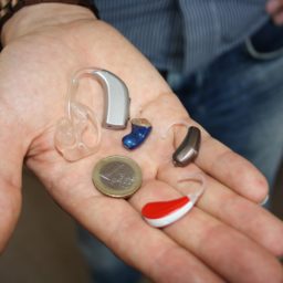 three different hearing aids and a coin