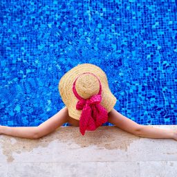 Birds eye view of a woman sitting in a pool with a sunhat