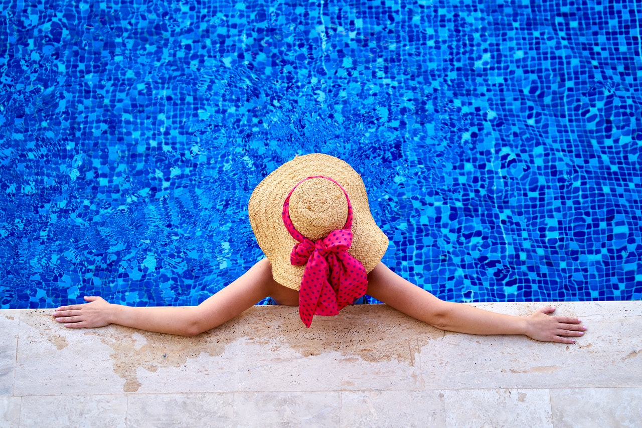 Birds eye view of a woman sitting in a pool with a sunhat 
