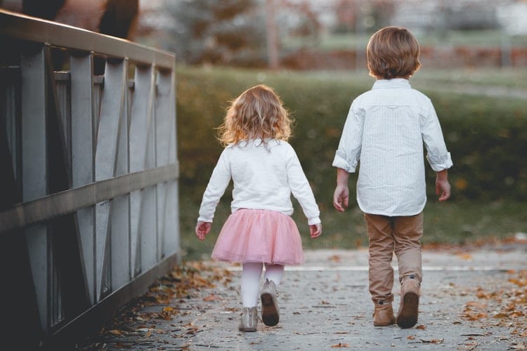 Two children walking on a bridge