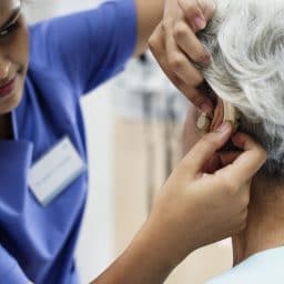 Woman gets a hearing aid fitted by an audiologist.