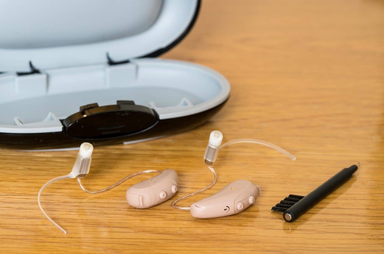 Hearing aids and a cleaning kit on a bedside table.