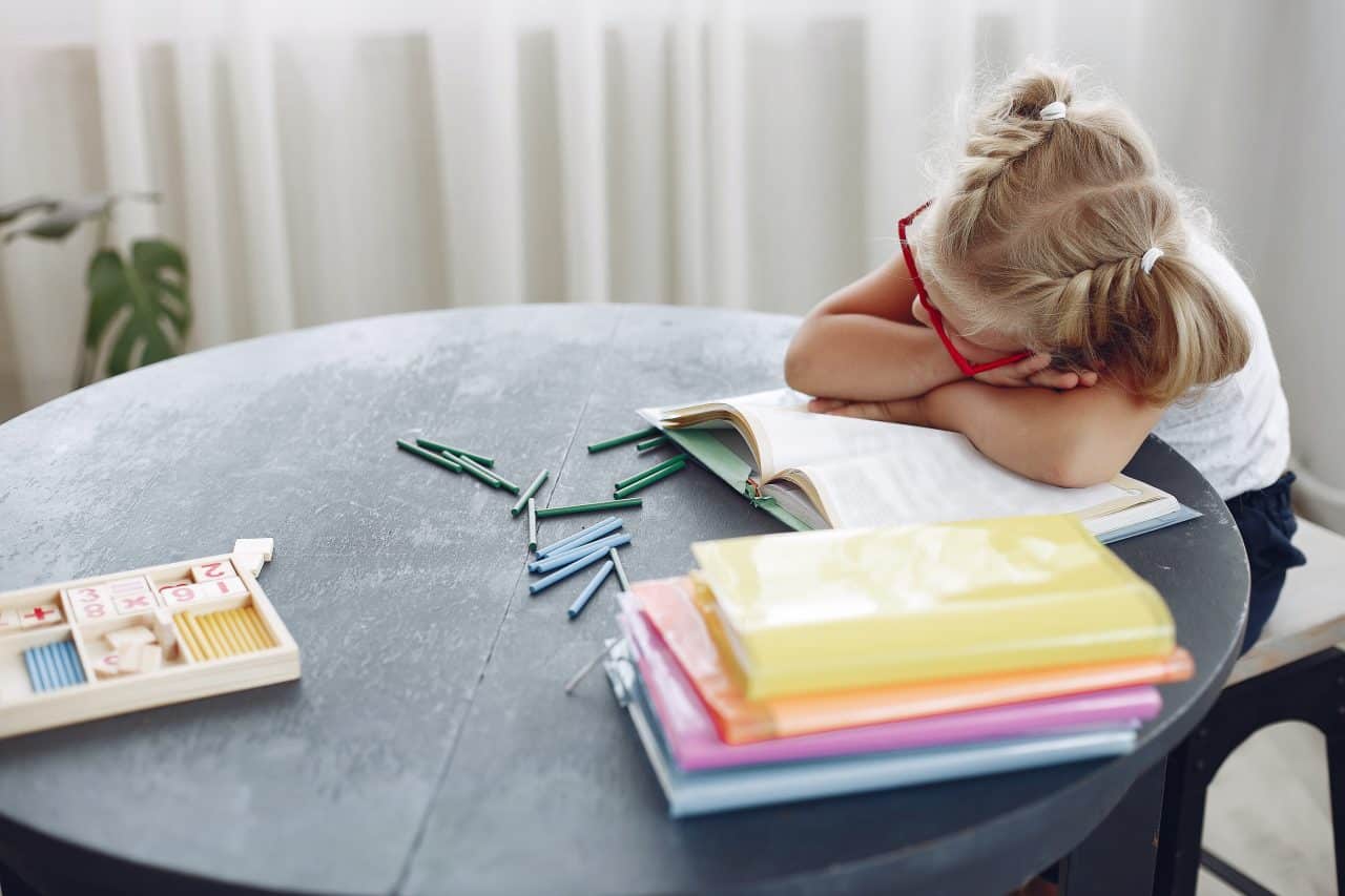 Little girl resting her head on her desk.