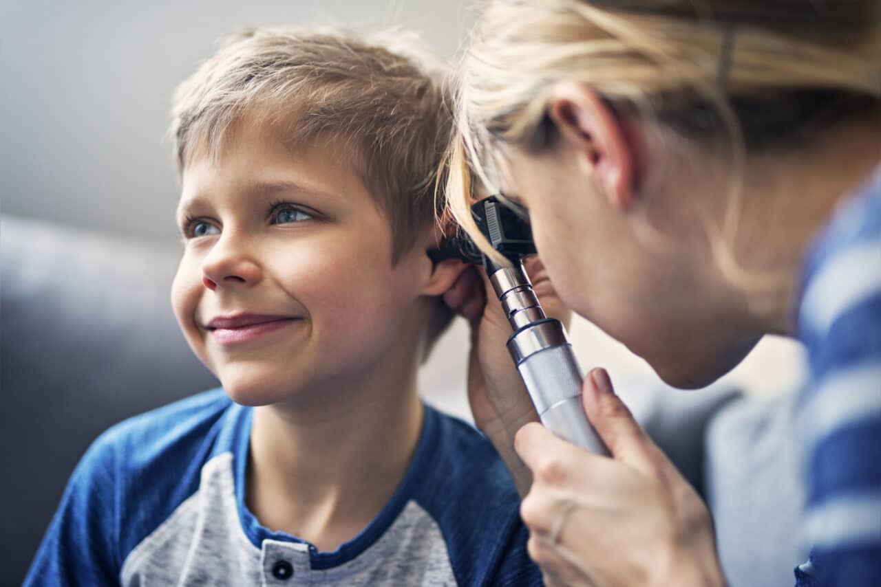 Young boy getting his ear examined by a doctor.