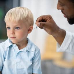 Audiologist fits a young boy with pediatric hearing aids.