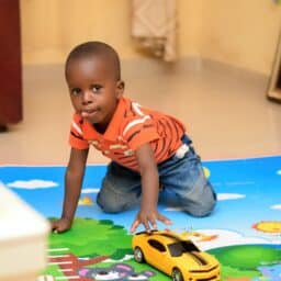 Little boy playing on a colorful mat in daycare.