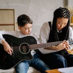 Woman giving guitar lessons to a young boy.