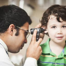 Toddler getting his ears examined by an audiologist.