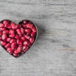 Pomegranate seeds in a heart shape on a table.