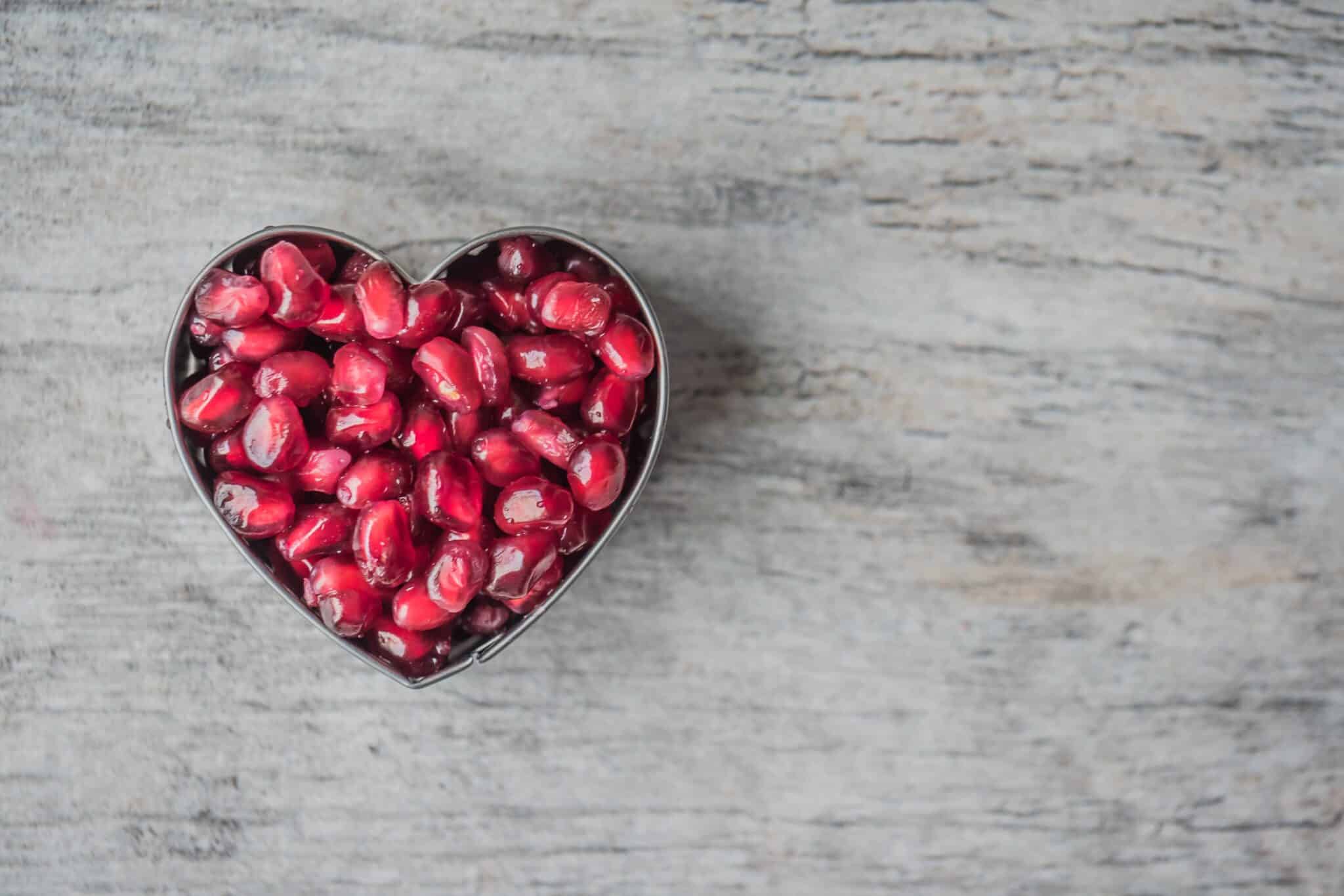 Pomegranate seeds in a heart shape on a table.