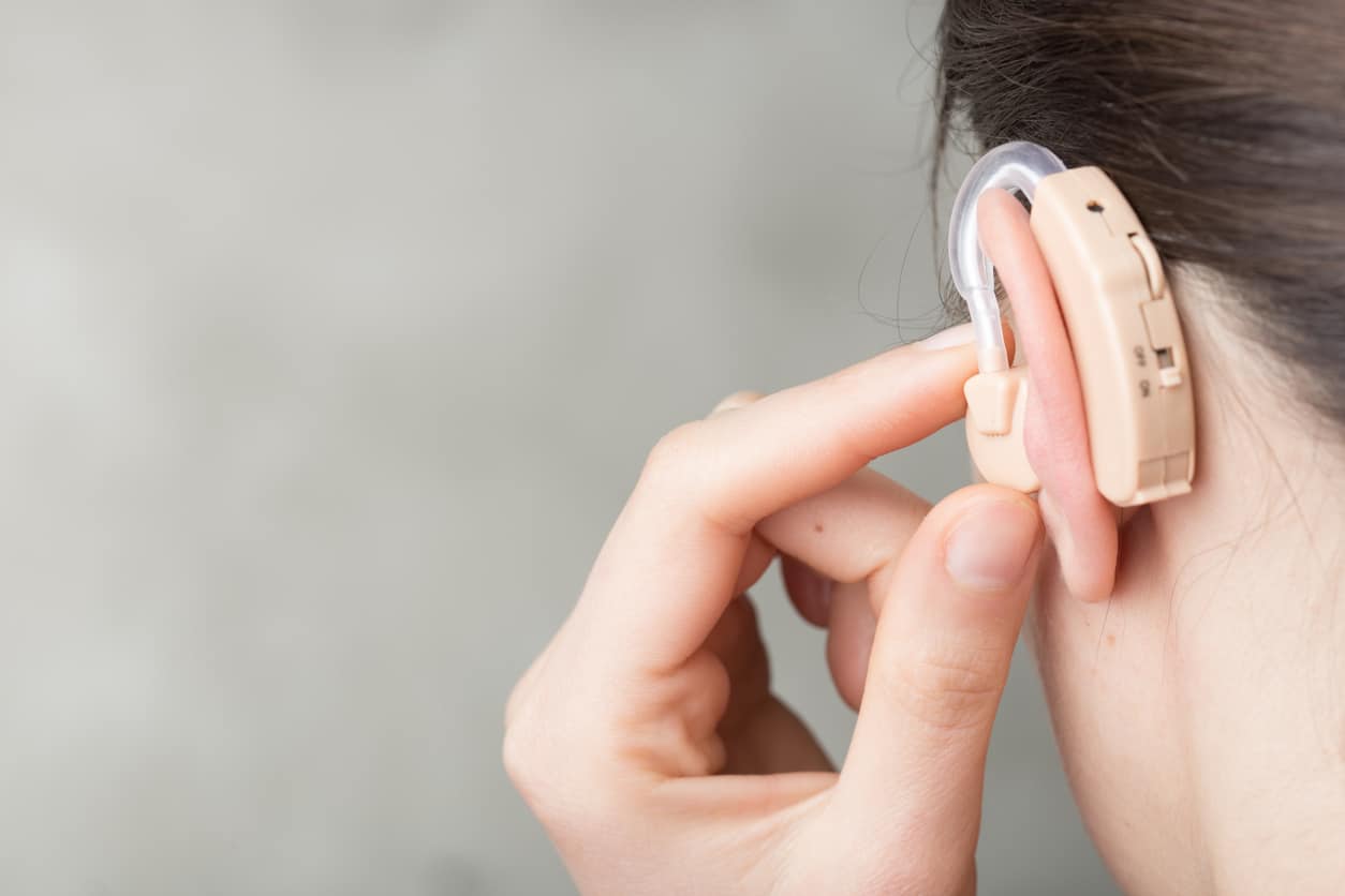 Close up view of a woman adjusting her hearing aid