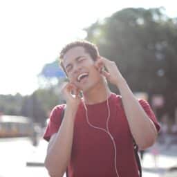 Young man listening to music on earbuds loudly.