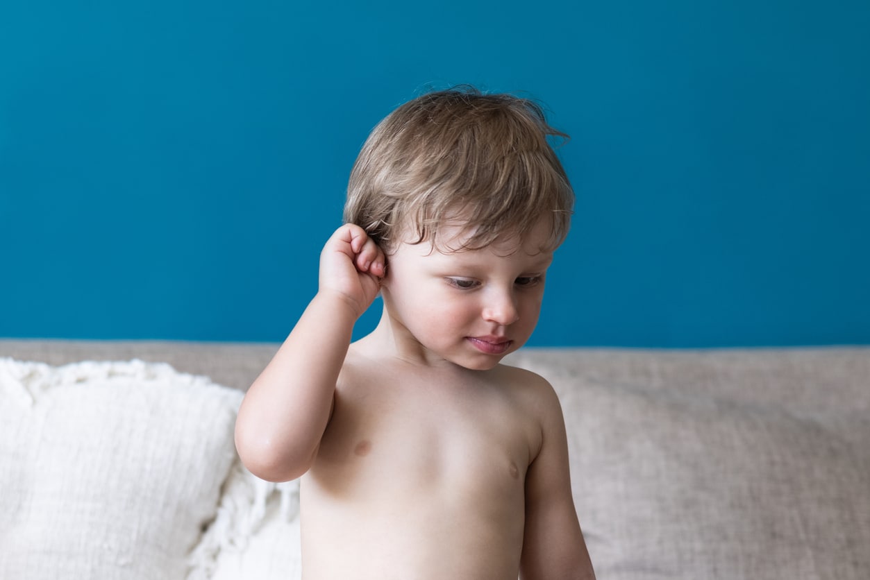 Child holds ear, appears in pain