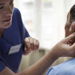 Audiologist adjusting a man's hearing aid
