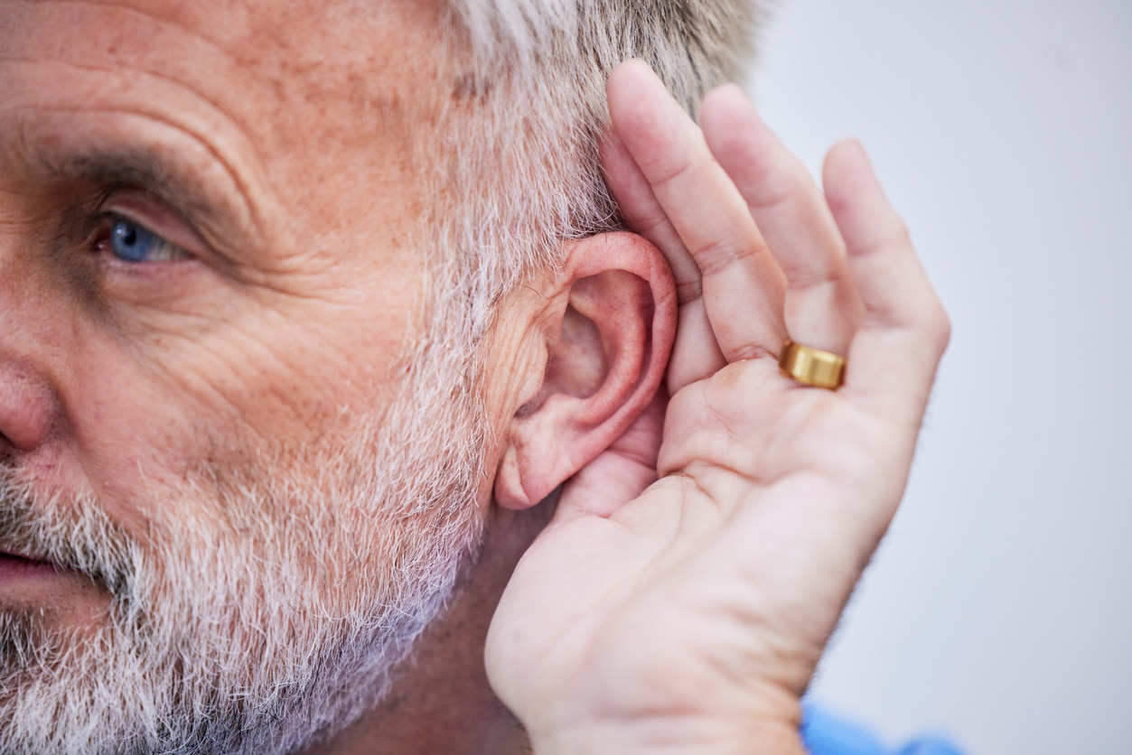 Man with hearing loss holds hand to ear