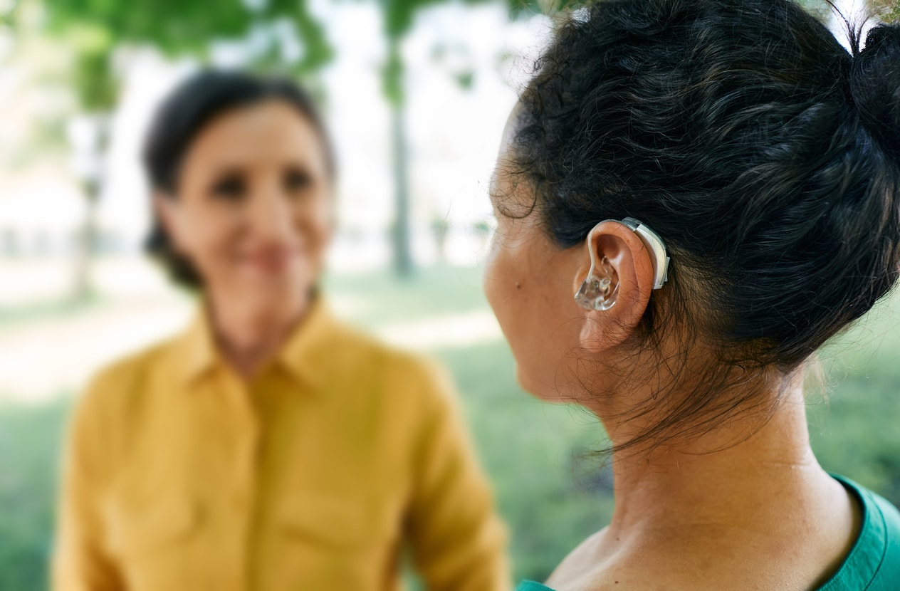 Woman with hearing loss talks to friends. 