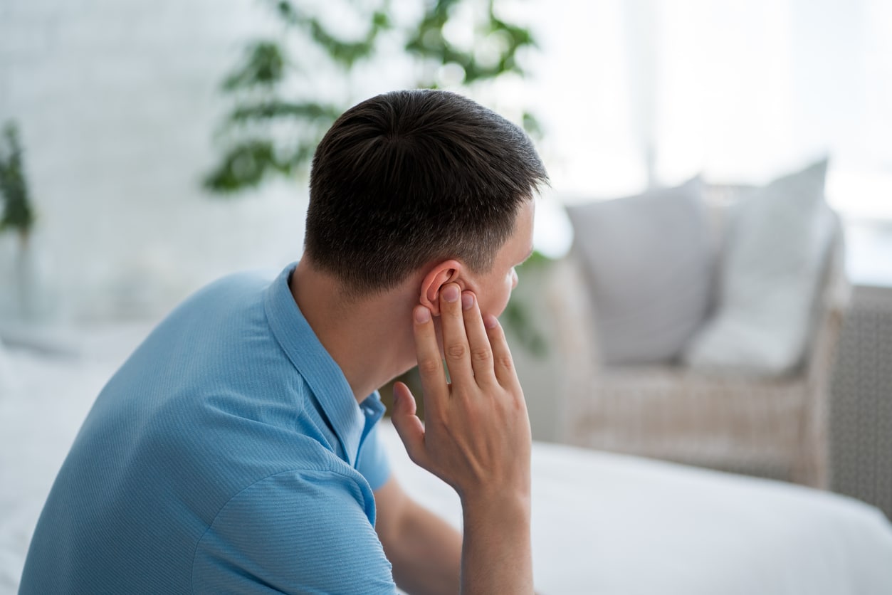 Man with tinnitus holding his ear.