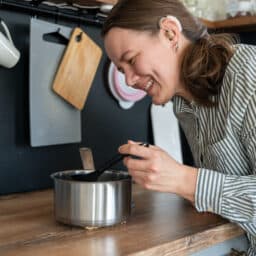 Woman with a hearing aid stirring a pot in the kitchen